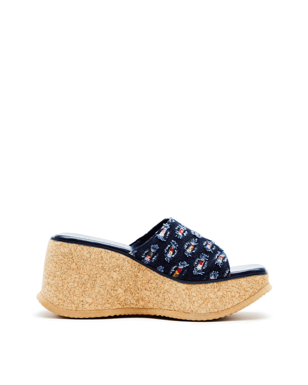 Blue denim platform slide sandal with cork wedge heel and textured pattern, on white background