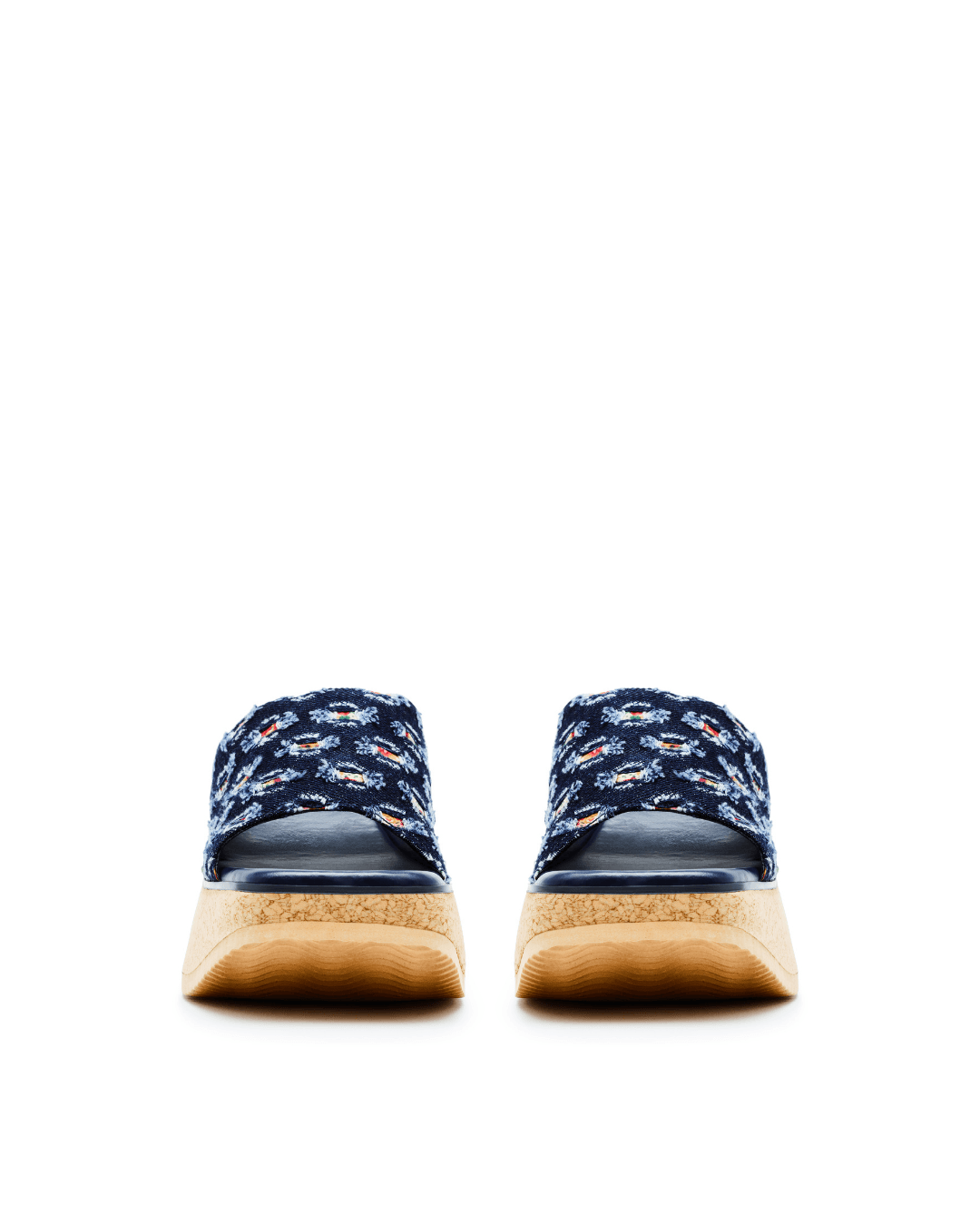 Blue denim platform slide sandals with floral pattern and tan cork soles on a white background