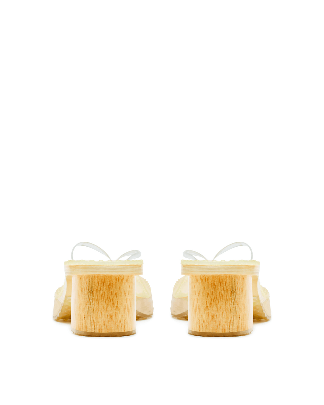Pair of platform sandals with light wood block heels and clear straps on a white background