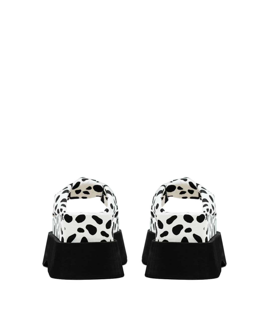 pair of black and white spotted platform slide sandals with thick black soles on white background