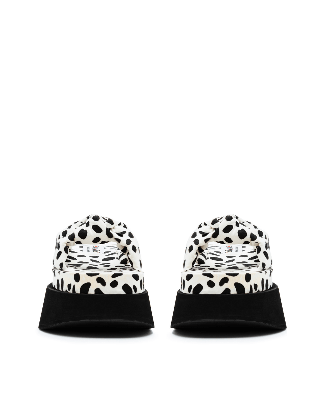 Pair of platform slide sandals with black and white spotted pattern and thick black soles