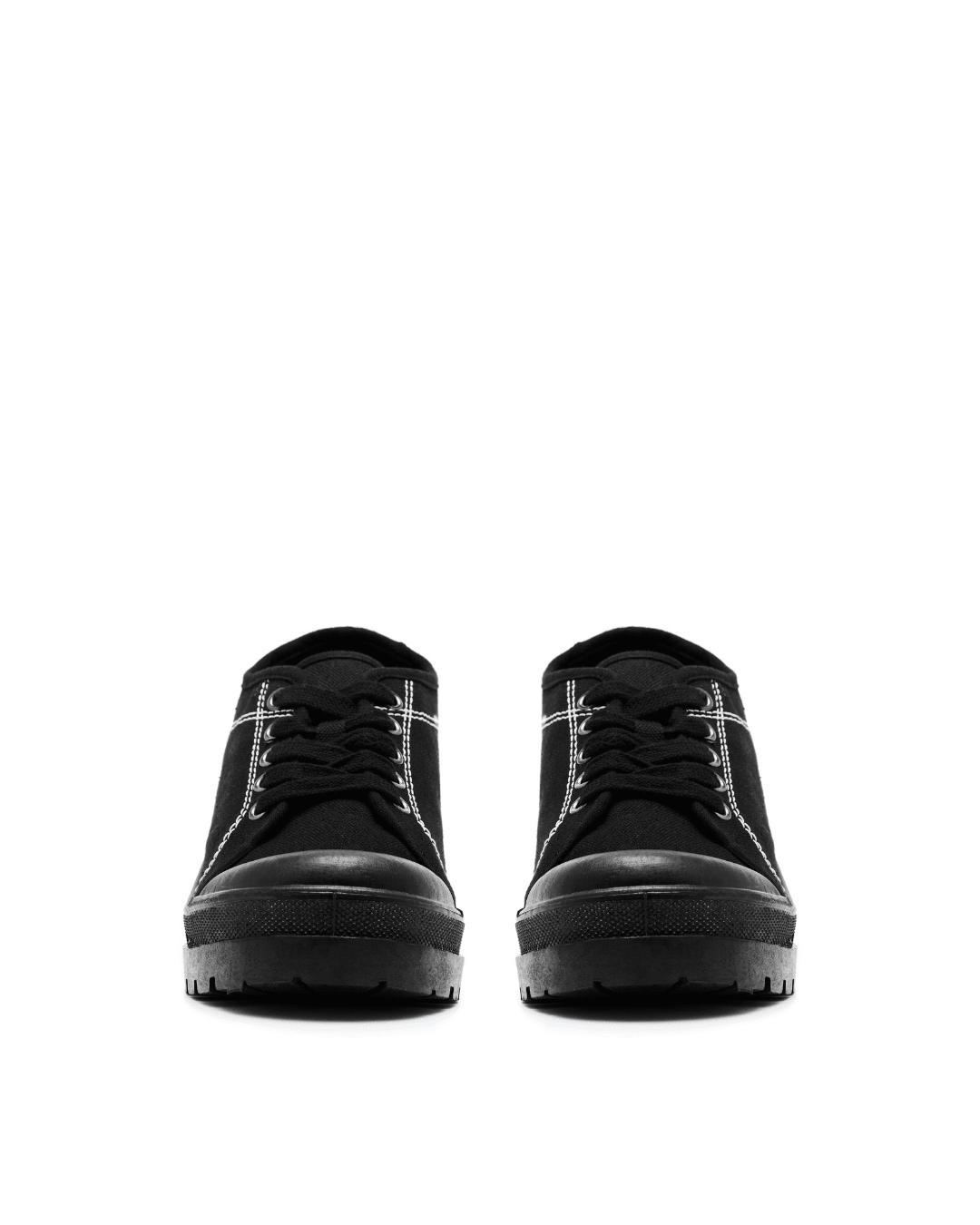 pair of black canvas lace-up sneakers with thick lug soles and white stitching on white background