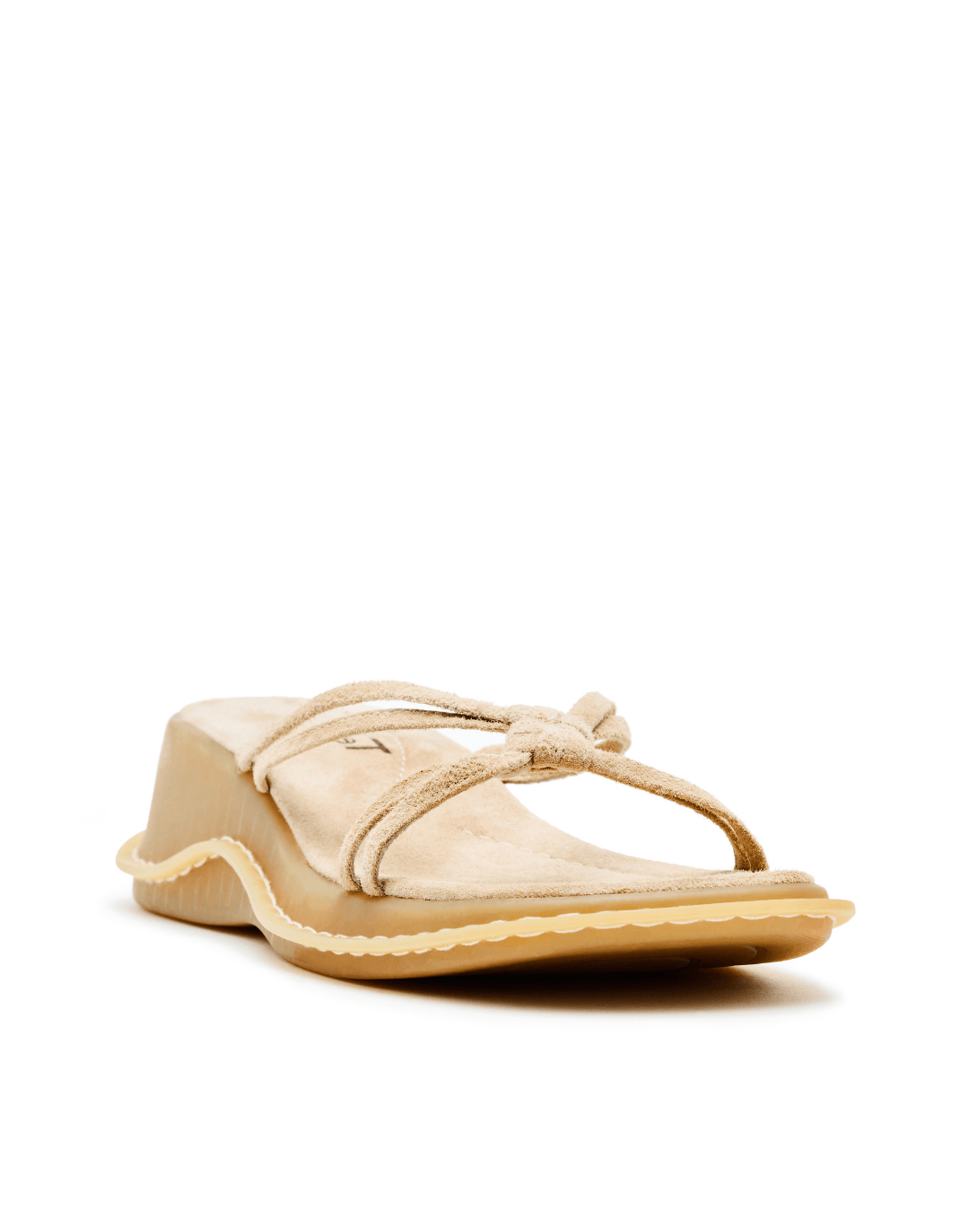 Beige suede wedge sandal with knot detail and textured sole on white background