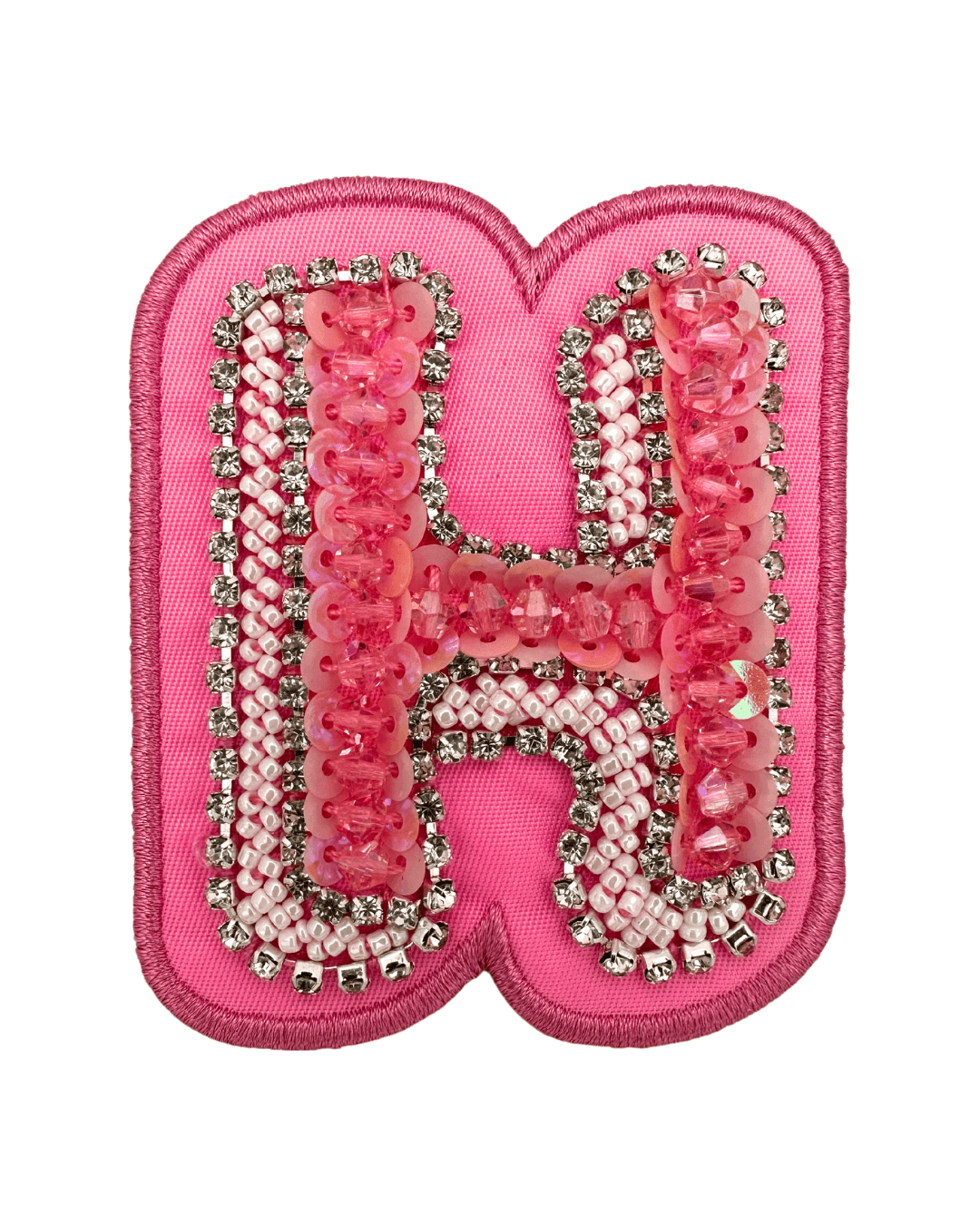 Pink embroidered letter patch with bead and rhinestone embellishments on fabric