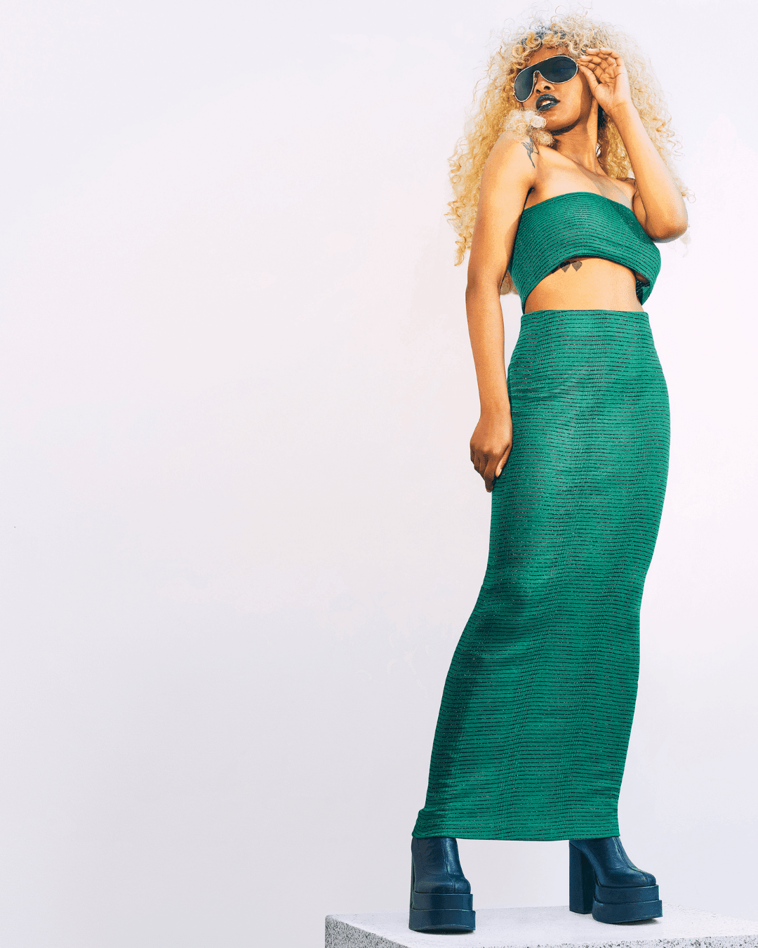 Woman wearing a green knit bandeau top and matching long skirt with black platform boots