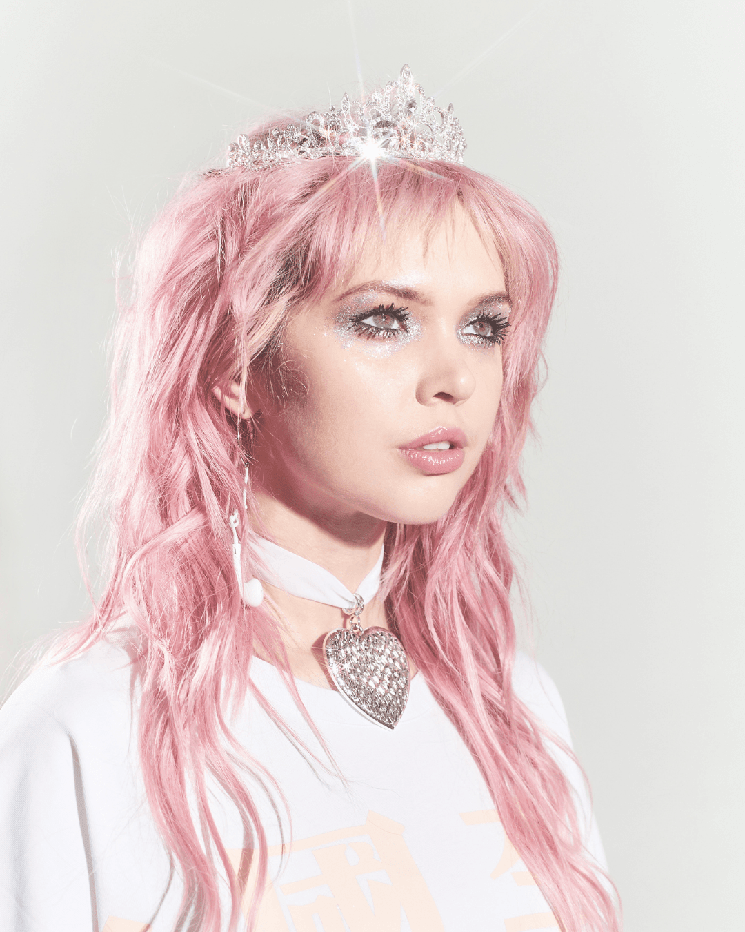 woman with pink hair wearing silver tiara, heart pendant choker, and white shirt