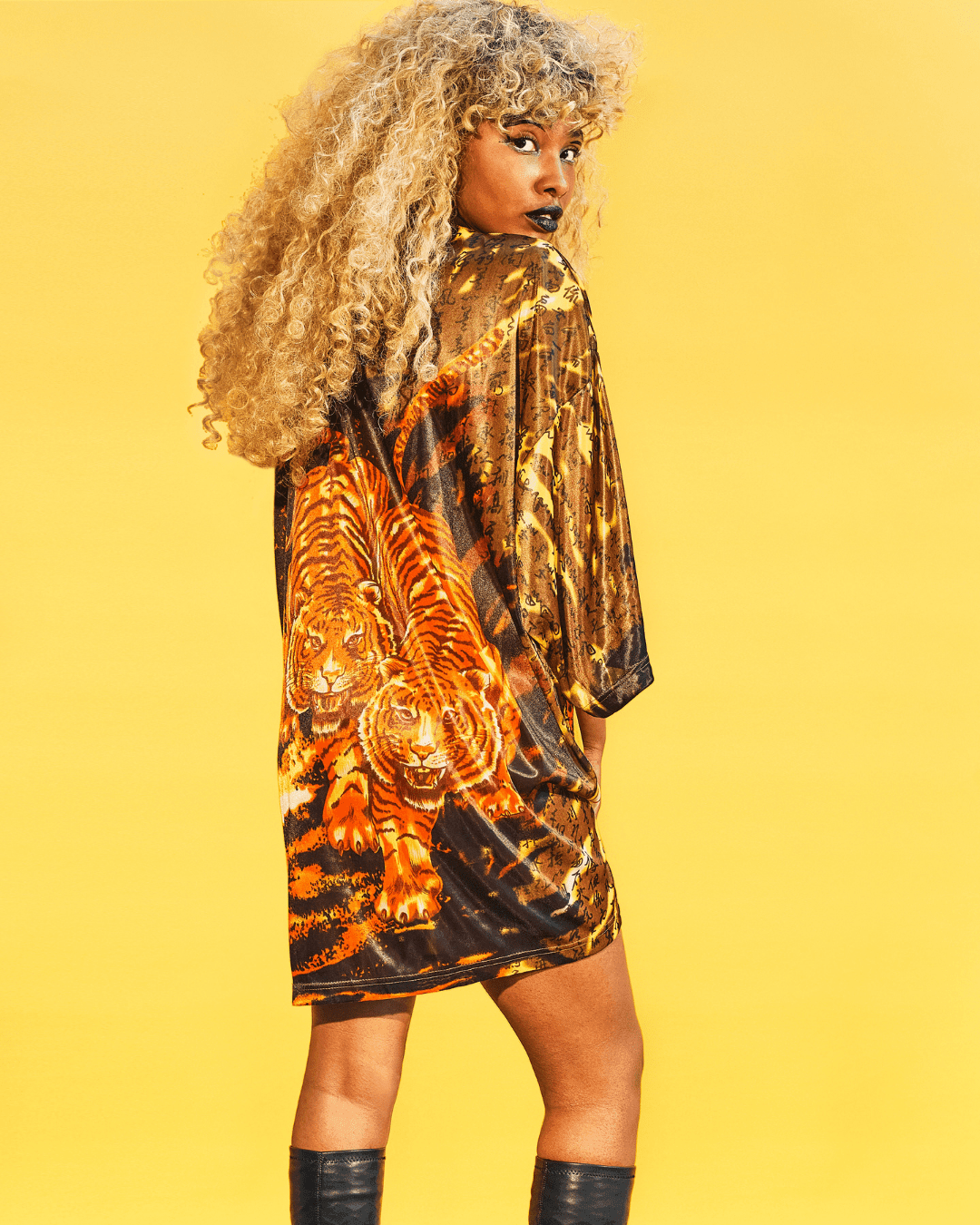 Woman wearing a loose black and orange t-shirt dress with tiger print on the back