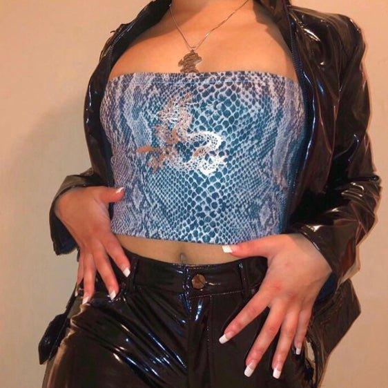 Woman wearing blue snakeskin tube top with silver dragon print and black patent pants