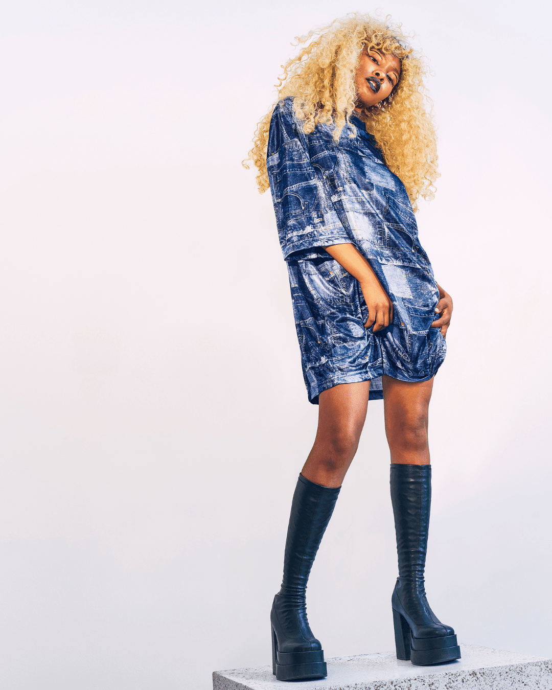 Person wearing a blue denim-pattern t-shirt dress and black knee-high platform boots