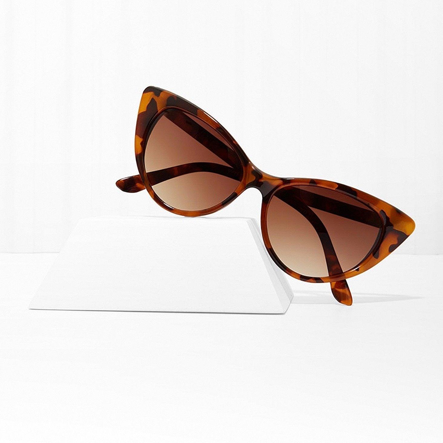 Amber tortoiseshell cat eye sunglasses with brown gradient lenses on white display stand