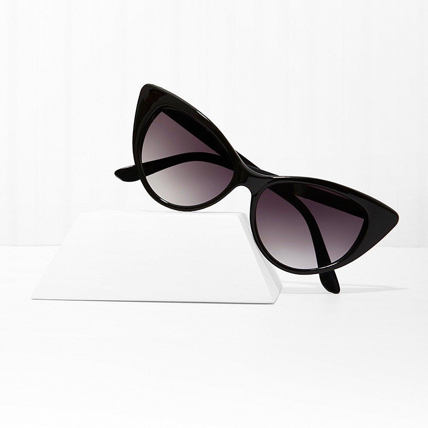 Black cat eye sunglasses with dark lenses on a white display stand