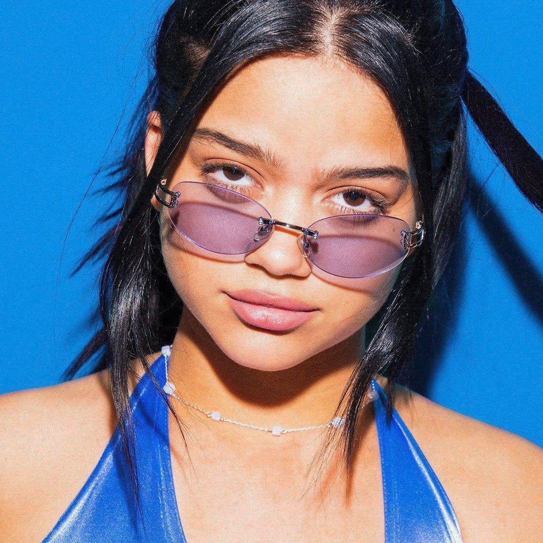 Silver agate bead necklace with small round stones on a woman's neck against a blue background.