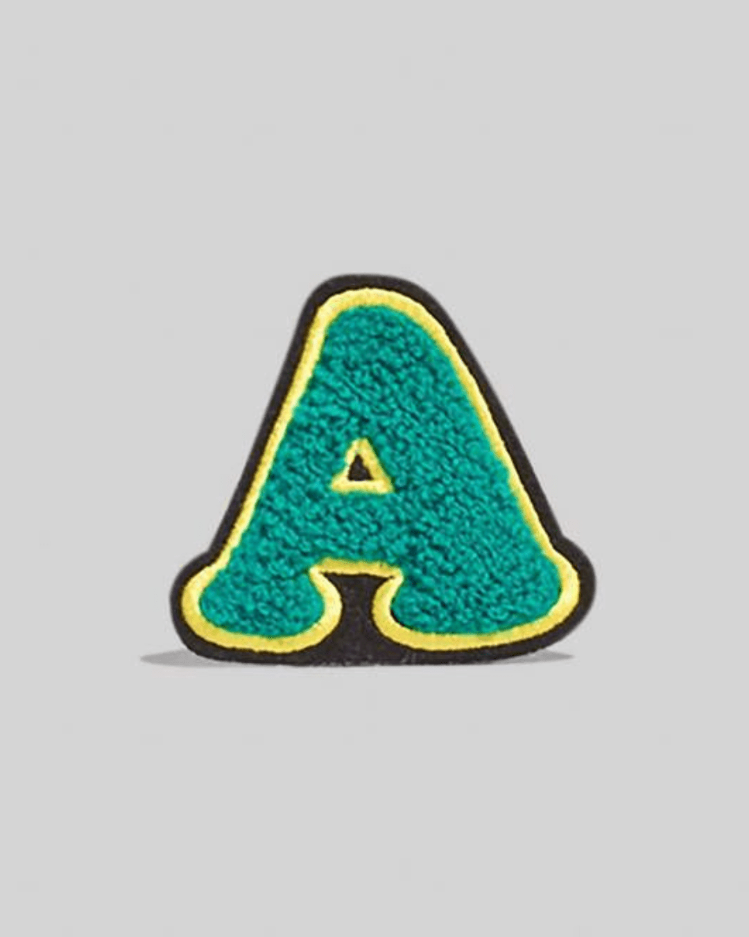 Large turquoise chenille letter A patch with yellow trim on a gray background