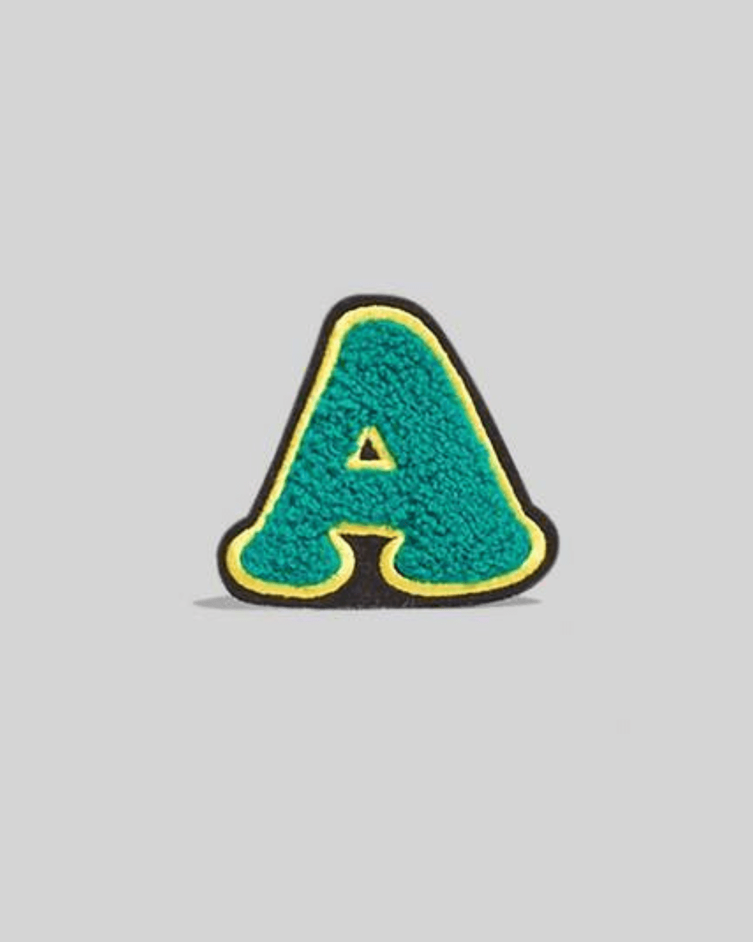 Turquoise chenille varsity letter A patch with yellow and black border on gray background