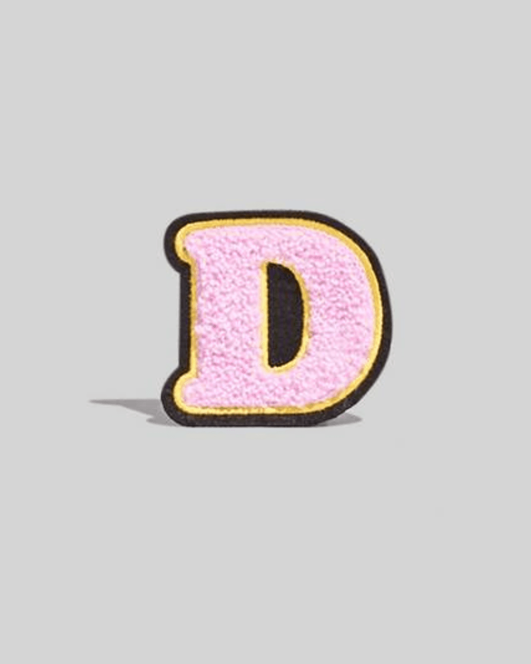 pink chenille varsity letter D patch with black and yellow border on gray background