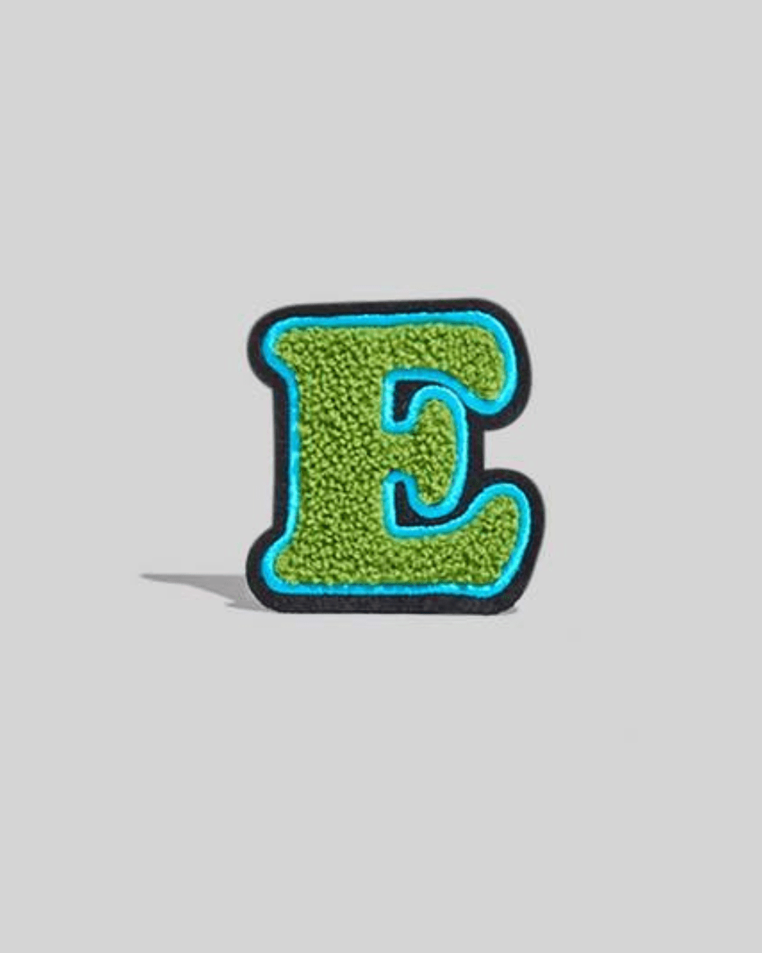 green chenille varsity letter E patch with blue and black border on gray background