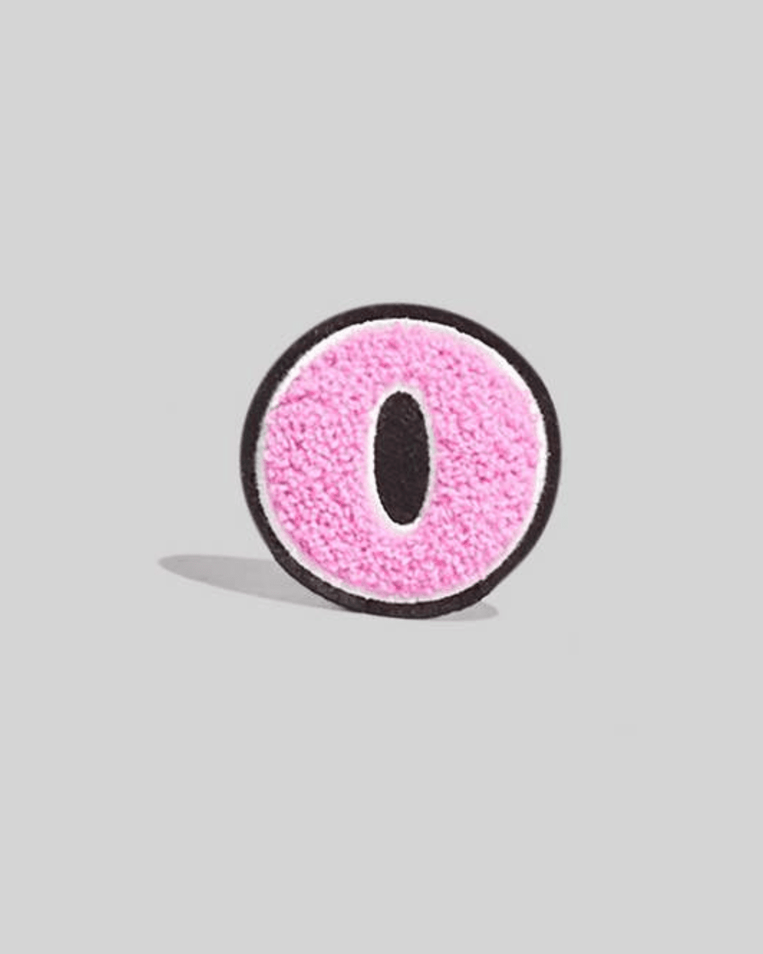 Pink chenille varsity letter O patch with black and white border on a gray background