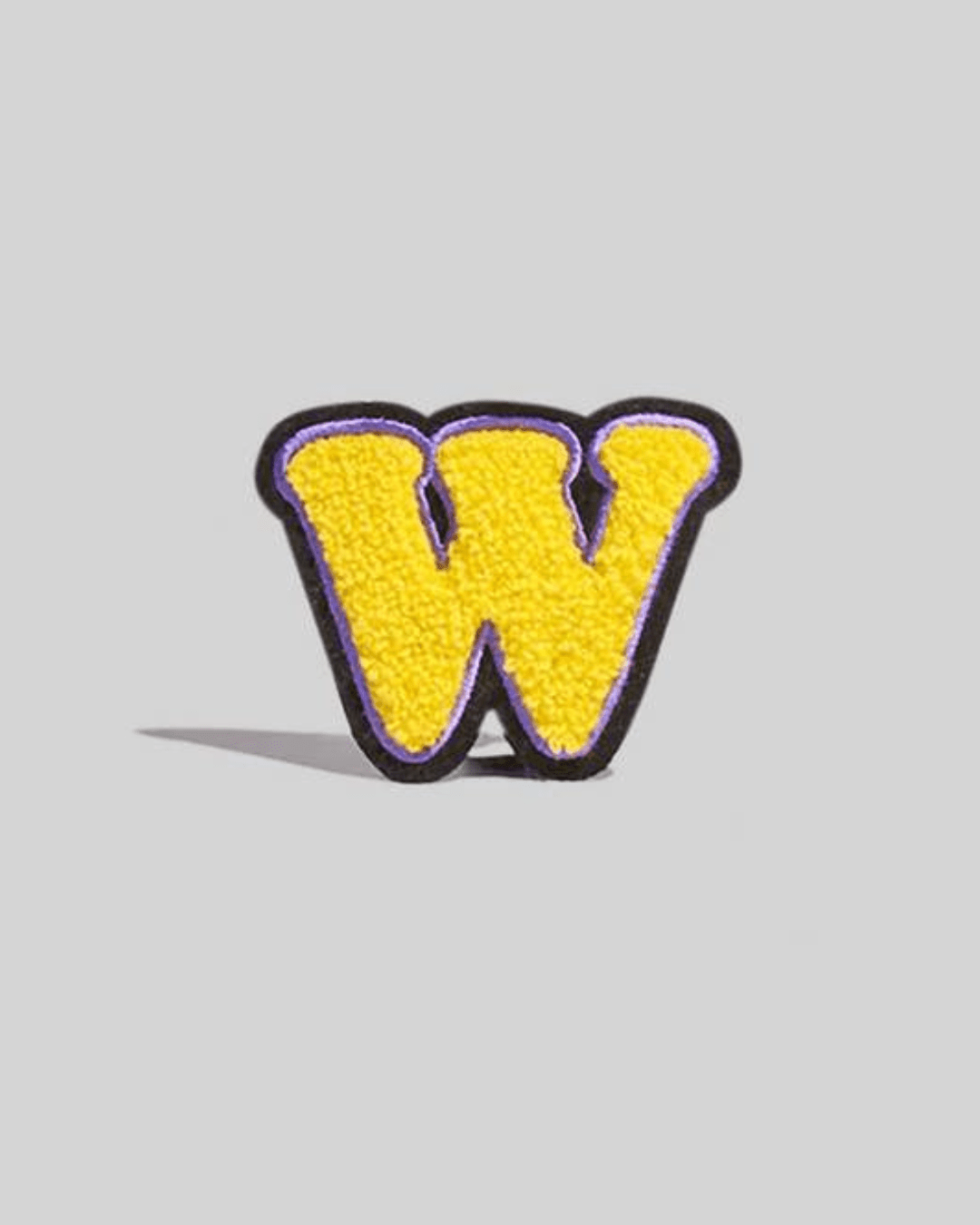 yellow chenille varsity letter W patch with black and purple border on a gray background