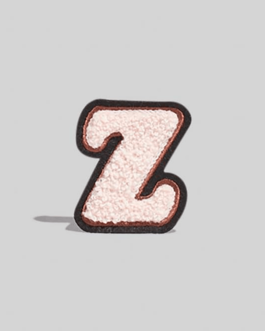 cream chenille varsity letter Z patch with black border on a gray background